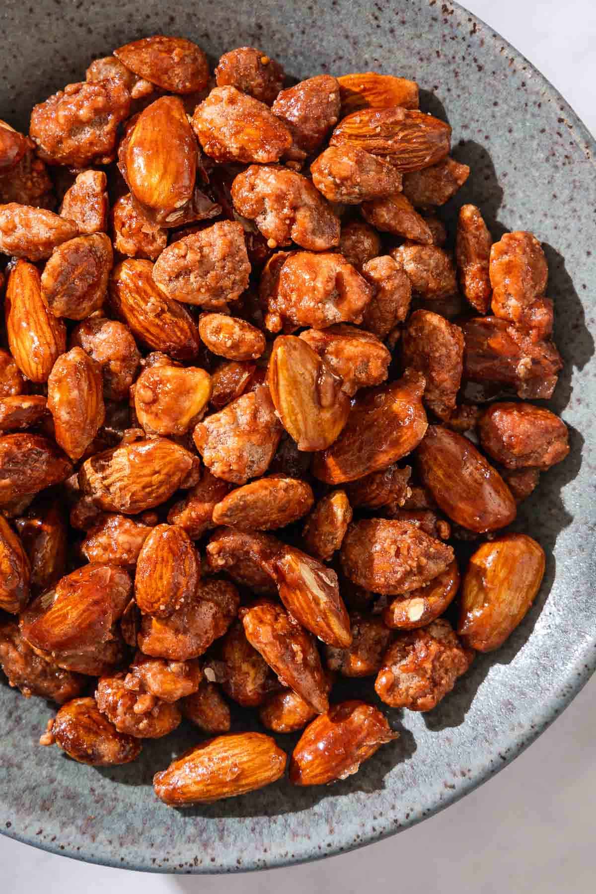 A close up of candied almonds in a bowl.