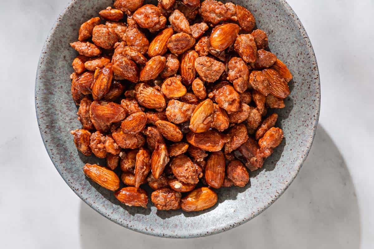 A close up of candied almonds in a bowl.