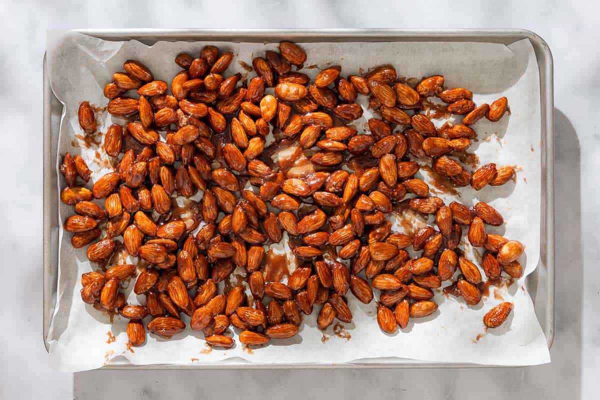 An overhead photo of candied almonds on a parchment lined baking sheet.