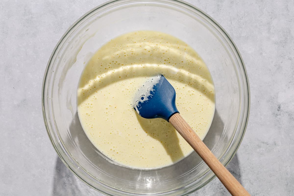 The wet ingredients for an Italian pear cake in a mixing bowl with a spatula.