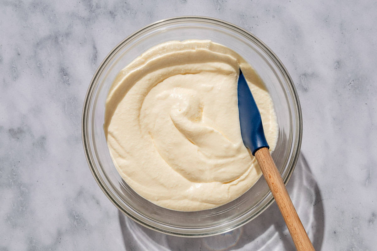 The yolk mixture combined with the mascarpone and egg whites in a bowl with a spatula.