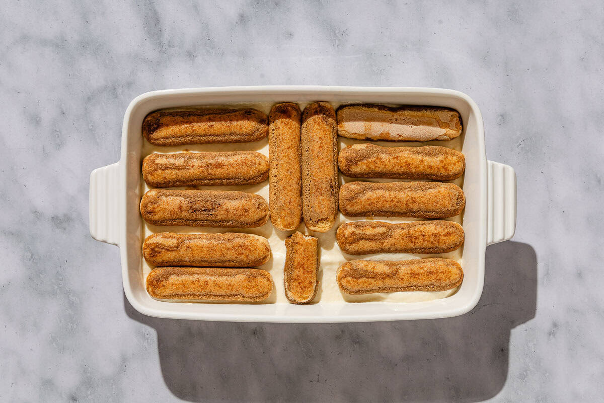 An overhead photo of the second layer of ladyfingers covering the mascarpone mixture in a baking dish.