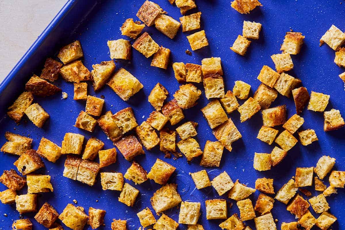 An overhead photo of baked croutons on a sheet pan.