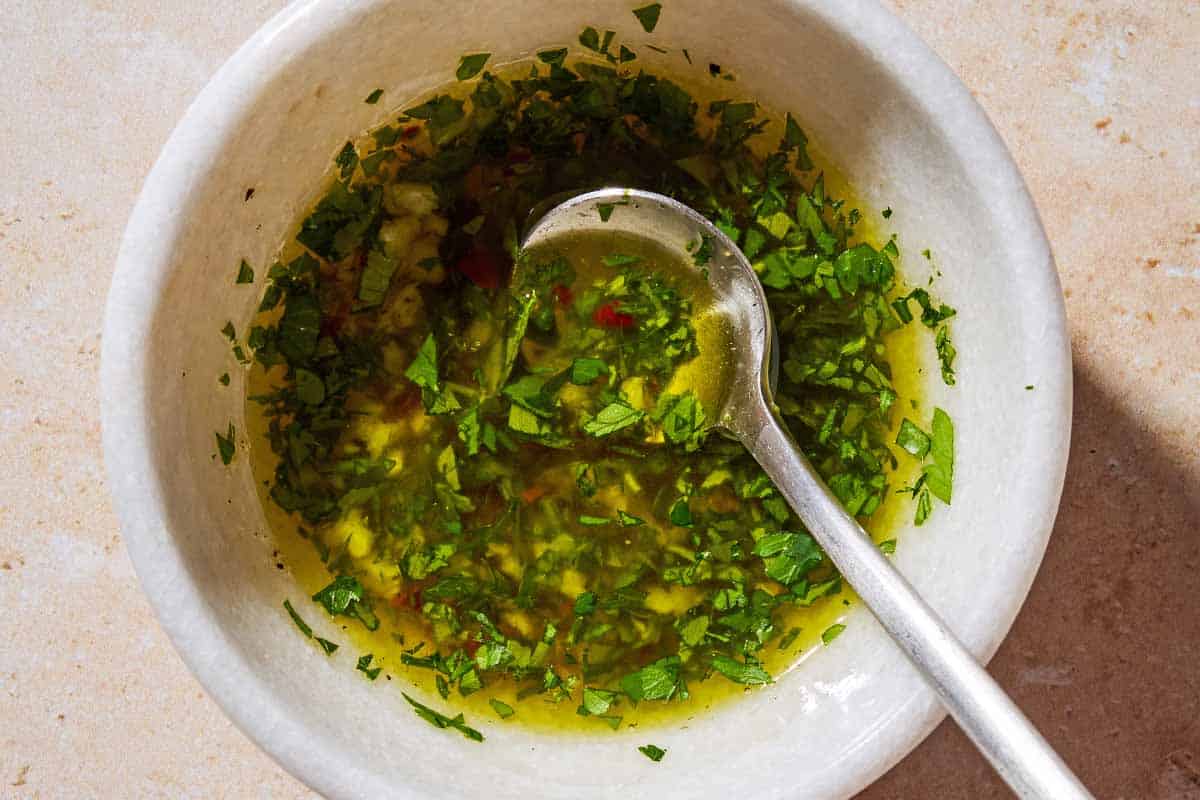 An overhead photo of the garlicky herb sauce in a bowl with a spoon.