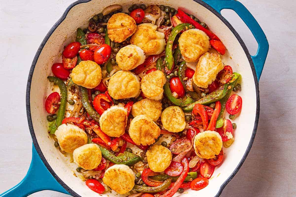 Mediterranean scallops nestled with tomatoes and bell peppers in a skillet.