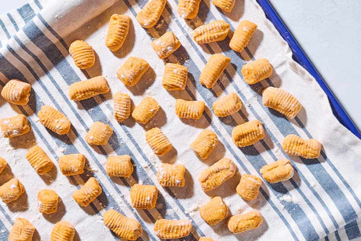 A close up of sweet potato gnocchi drying on a kitchen towel.