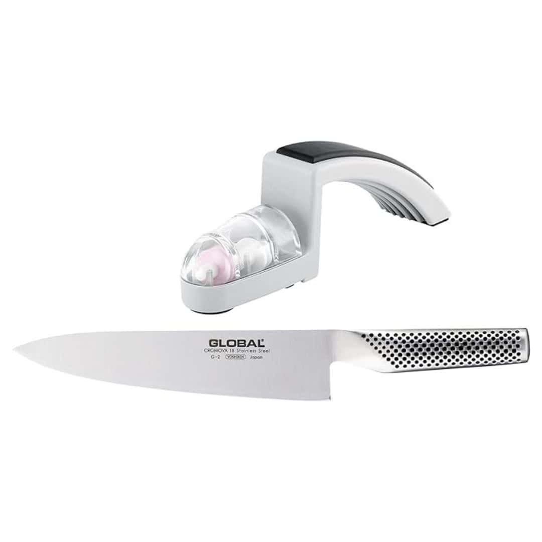 Stainless steel chef's knife with the GLOBAL logo and a silver knife sharpener above it. They are both floating on a white background and the sharpener has a rubber grip handle.