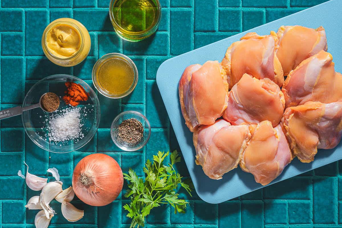 Ingredients for garlic dijon chicken including chicken thighs, salt, black pepper, onion, garlic, parsley, dijon mustard, honey, olive oil, coriander, paprika, and cayenne pepper.