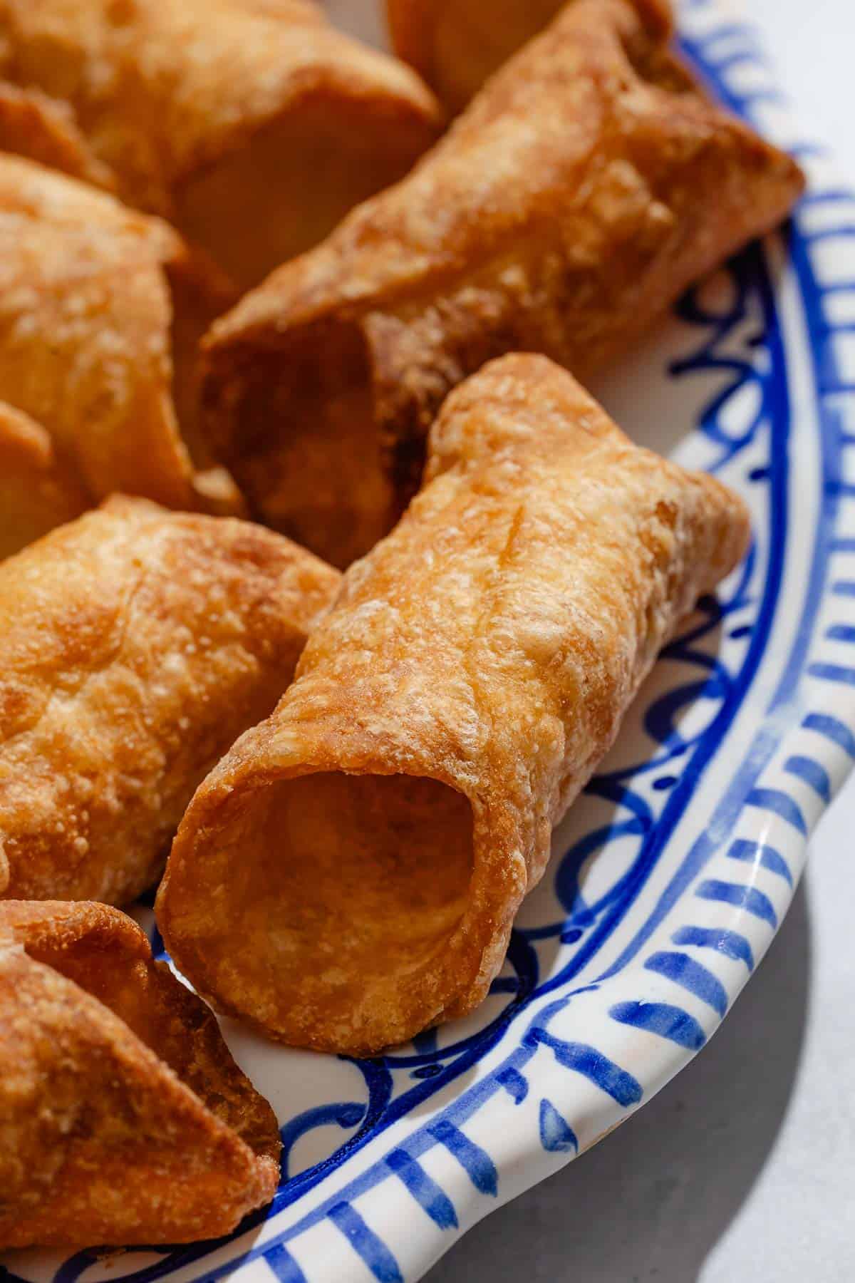 A close up of several cannoli shells on a plate.