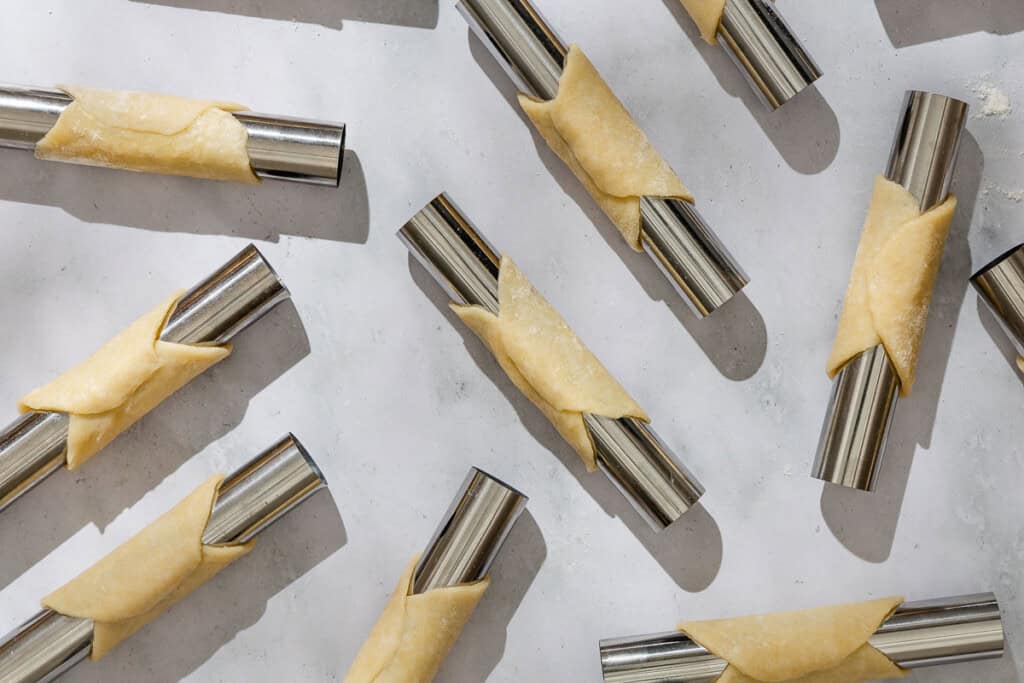 An overhead photo of several pastry circles wrapped around cannoli molds.