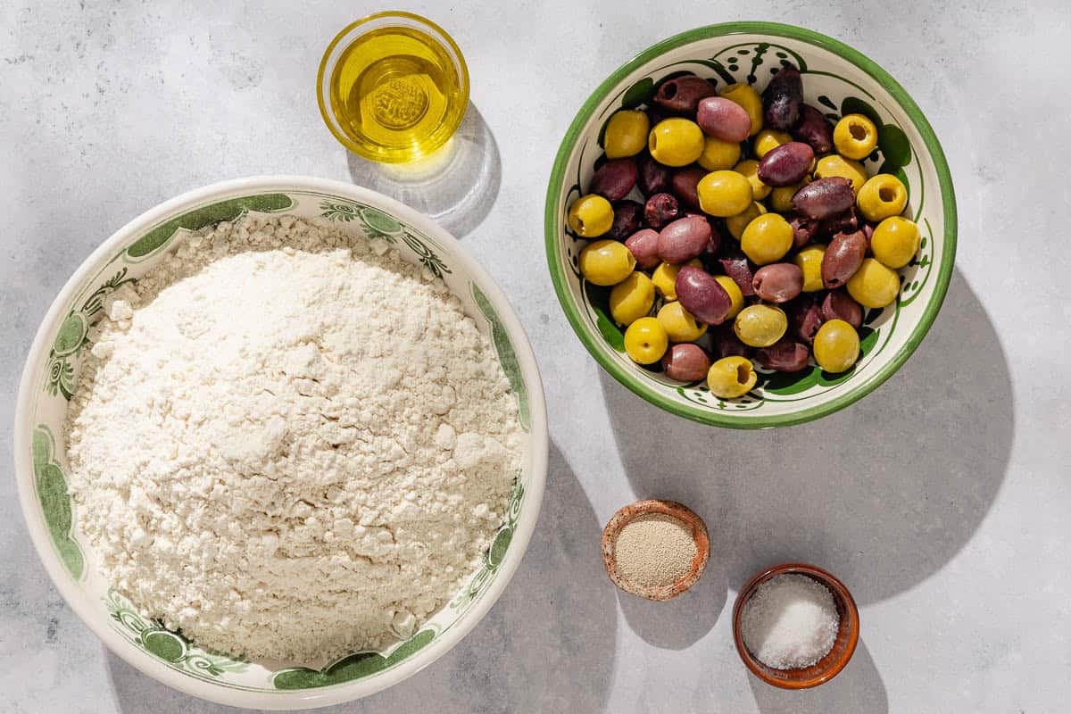 Ingredients for olive bread including bread flour, kosher salt, instant yeast, water, pitted olives, and olive oil.