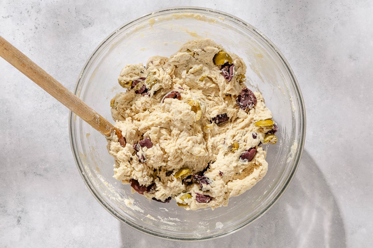 An overhead photo of the olive bread dough just after being mixed together with a wooden spoon.