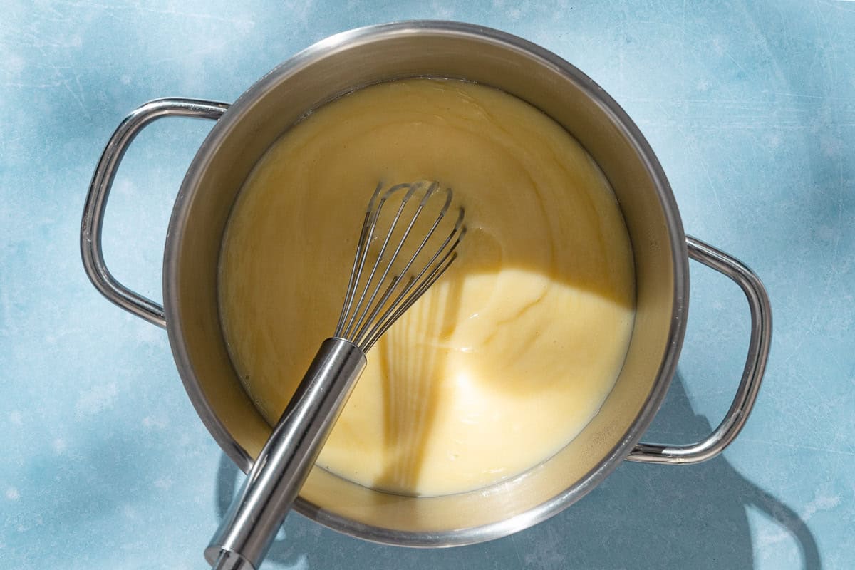 An overhead photo of the filling for the lemon curd tart in a large pot with a whisk.