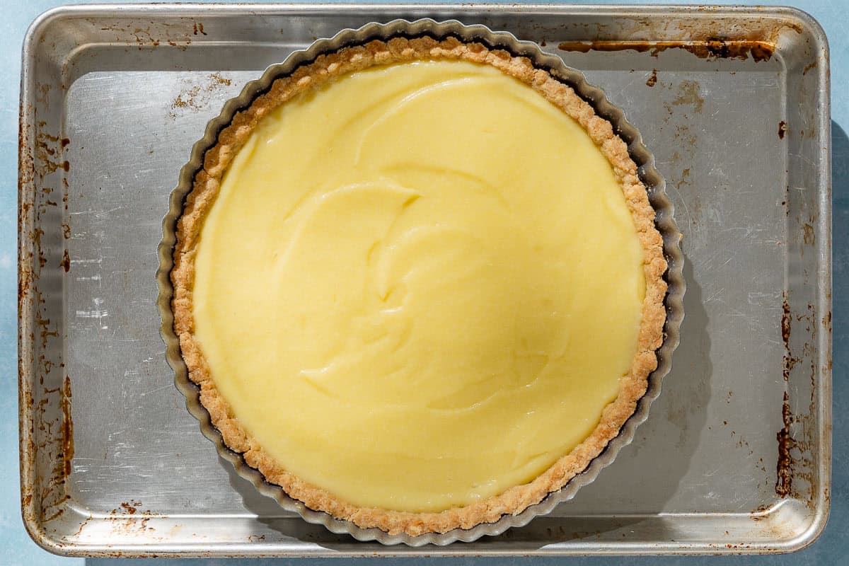 An overhead photo of an unbaked lemon tart in a tart pan on a baking sheet.