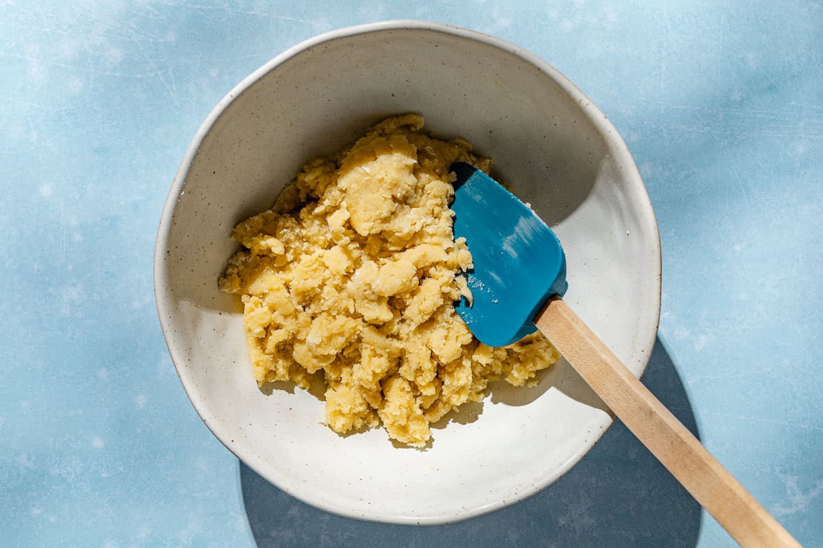 An overhead photo of the dough for the lemon curd tart in a mixing bowl with a spatula.