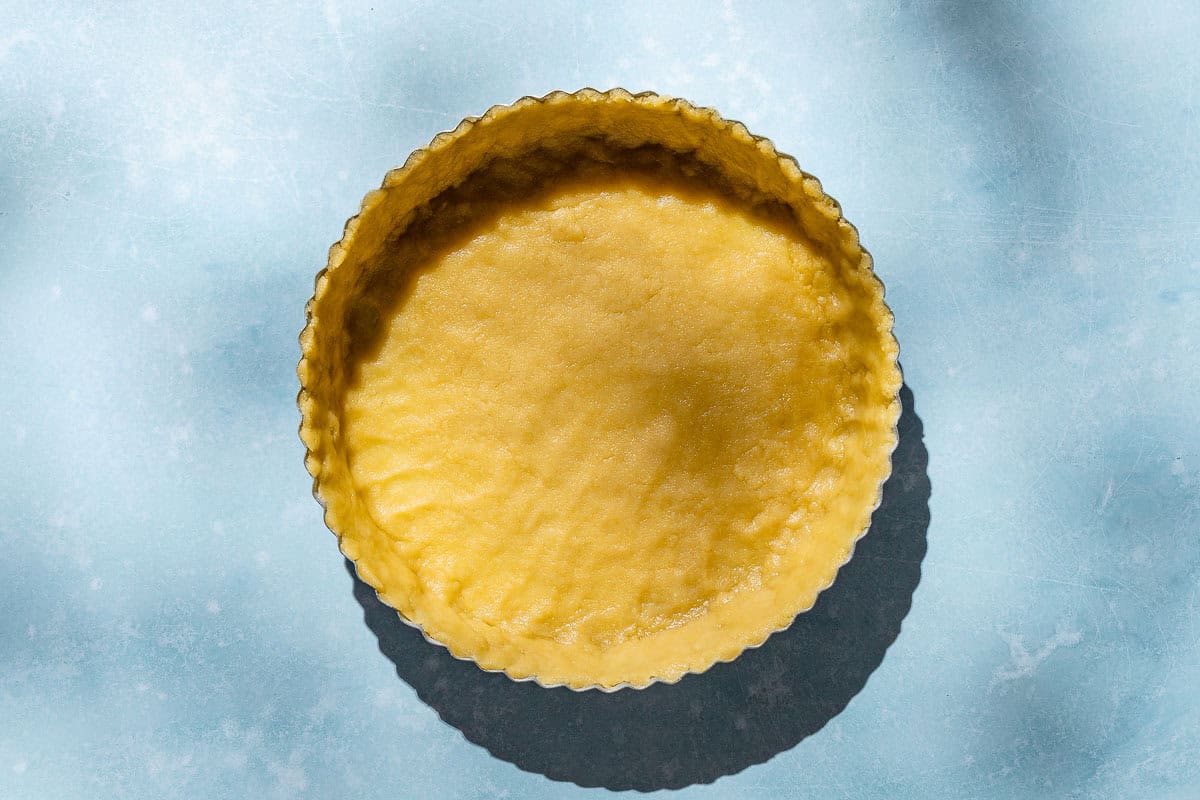 An overhead photo of unbaked dough pressed into a tart pan.