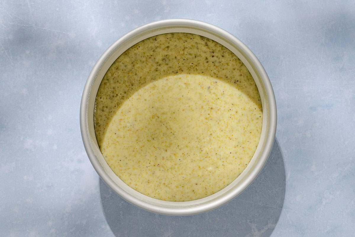 An overhead photo of the batter for the pistachio cake in a round baking pan.