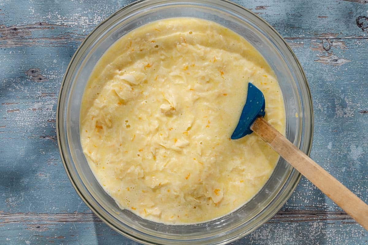 An overhead photo of the batter for the portokalopita greek orange cake mixed together in a bowl with a spatula.