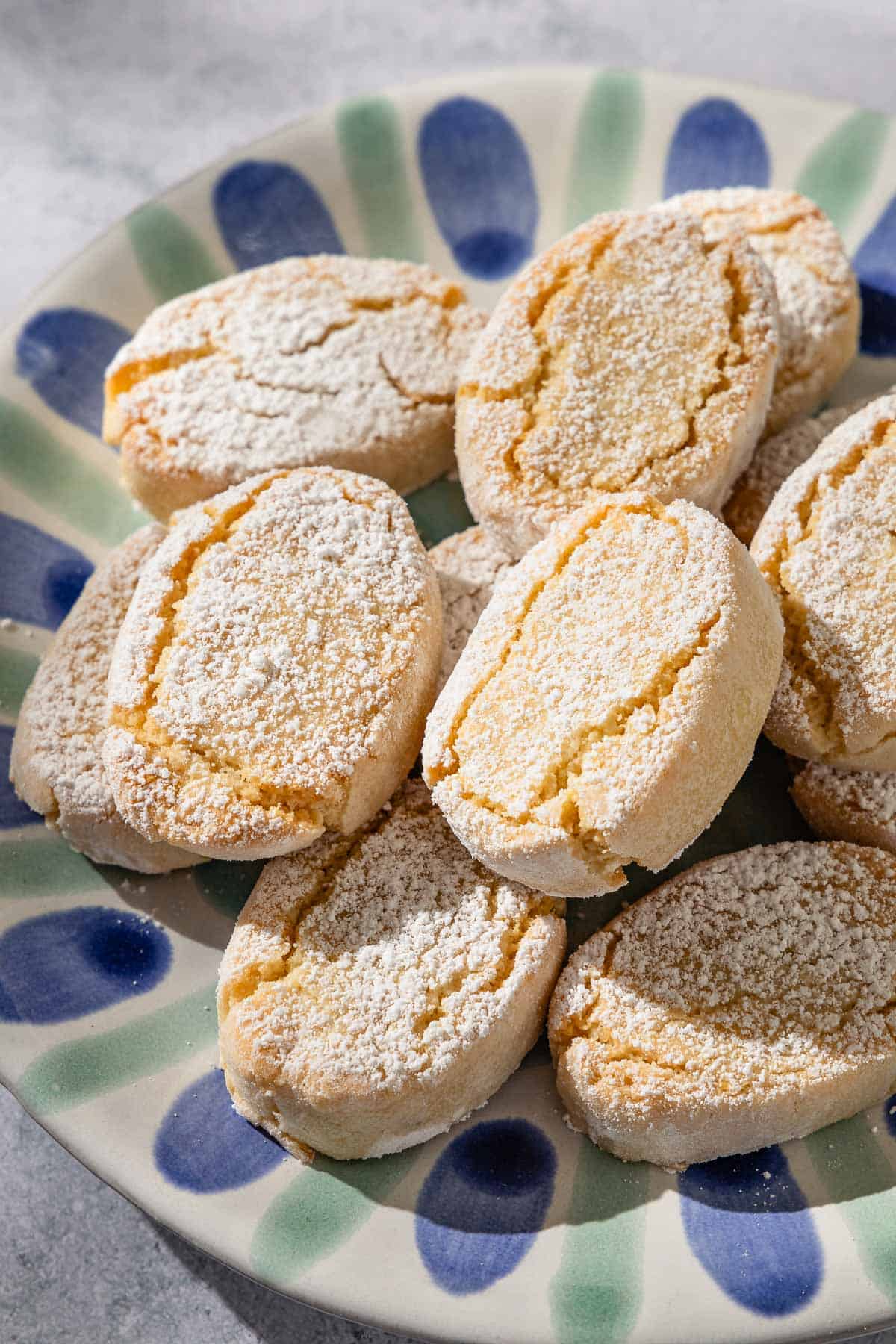 A close up of baked ricciarelli cookies topped with powdered sugar on a plate.