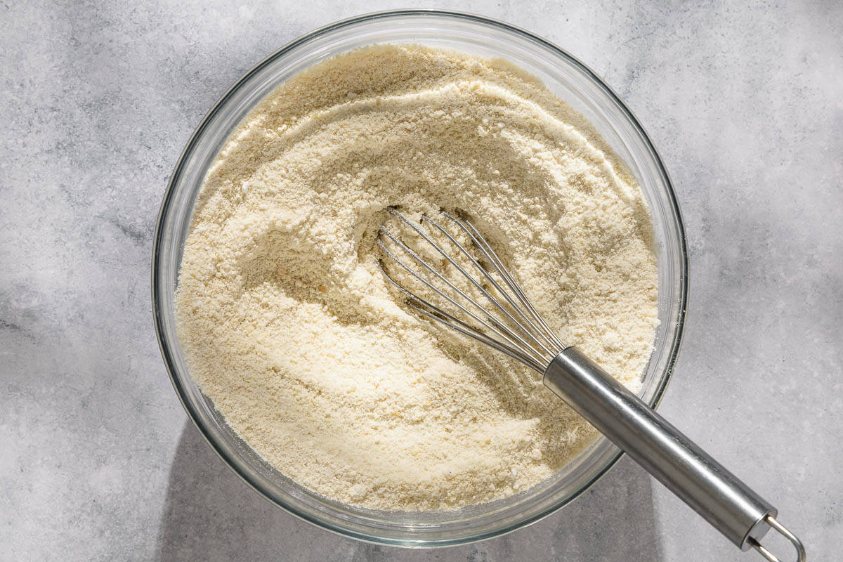 The dry ingredients for the ricciarelli cookies mixed together in a bowl with a whisk.