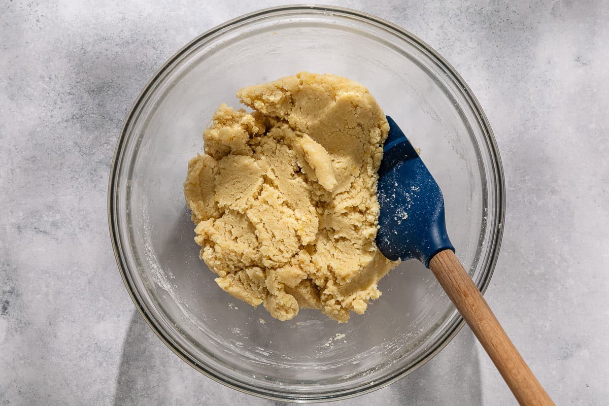 The dough for the ricciarelli cookies in a bowl with a spatula.