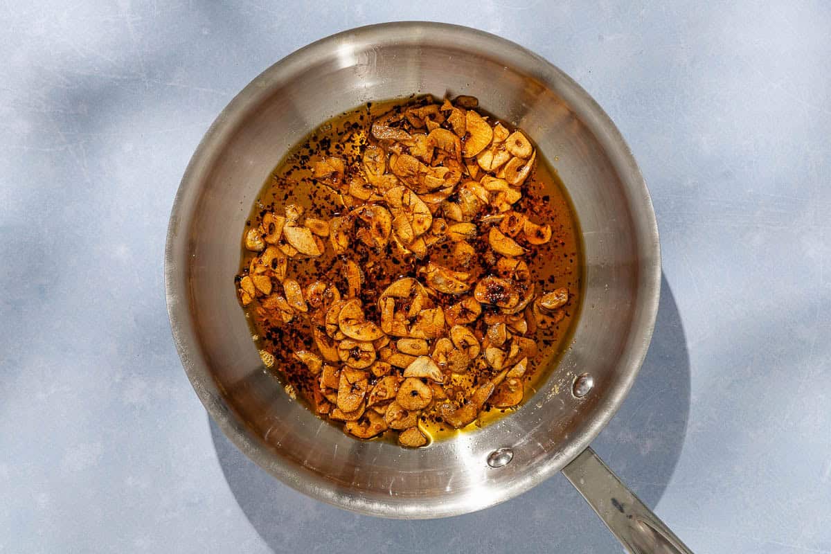 On overhead photo of the fried garlic and aleppo oil in a frying pan.