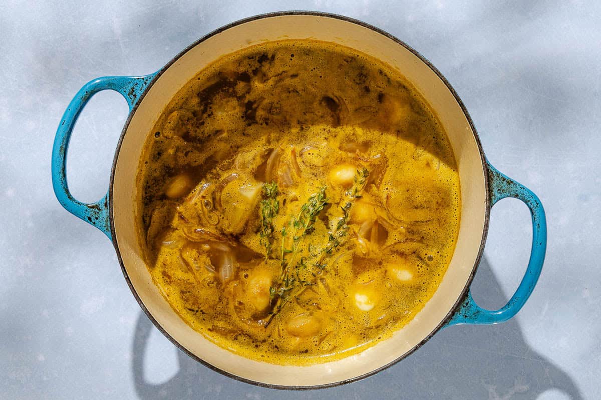 An overhead photo of the garlic soup simmering in a large pot before being blended.