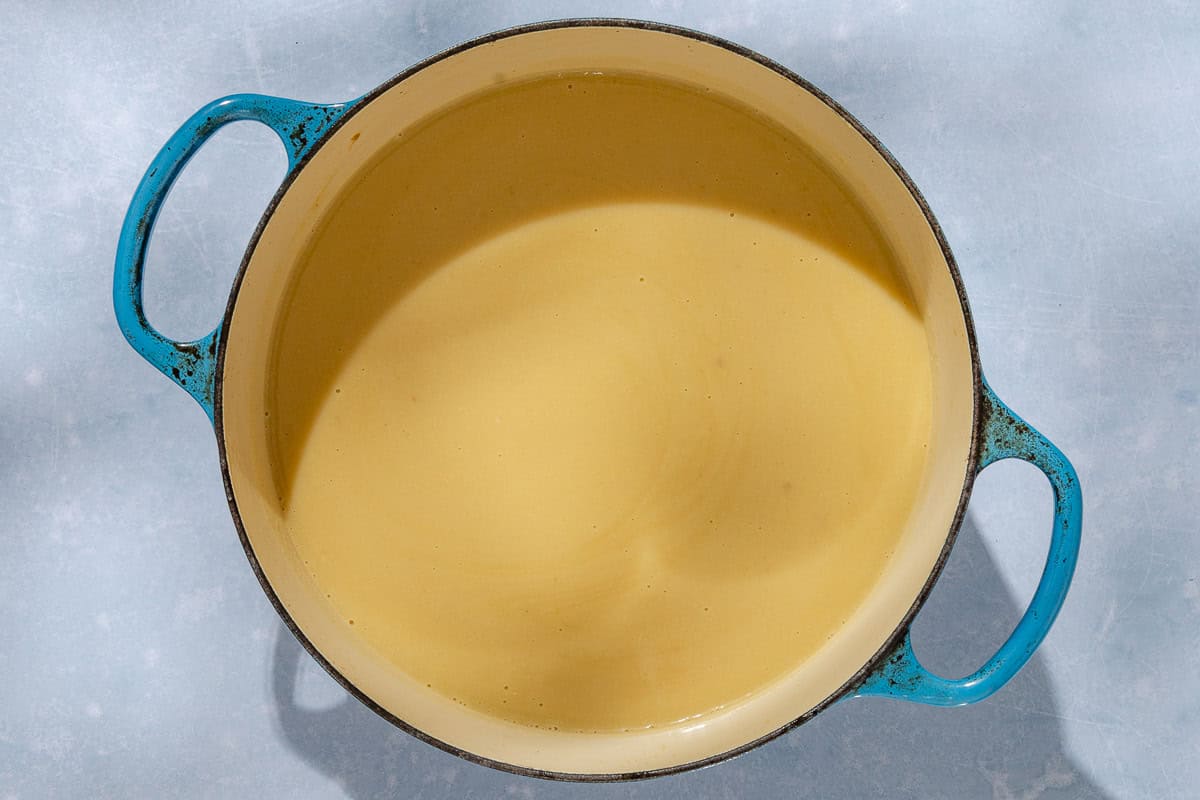 An overhead photo of garlic soup topped in a large pot.