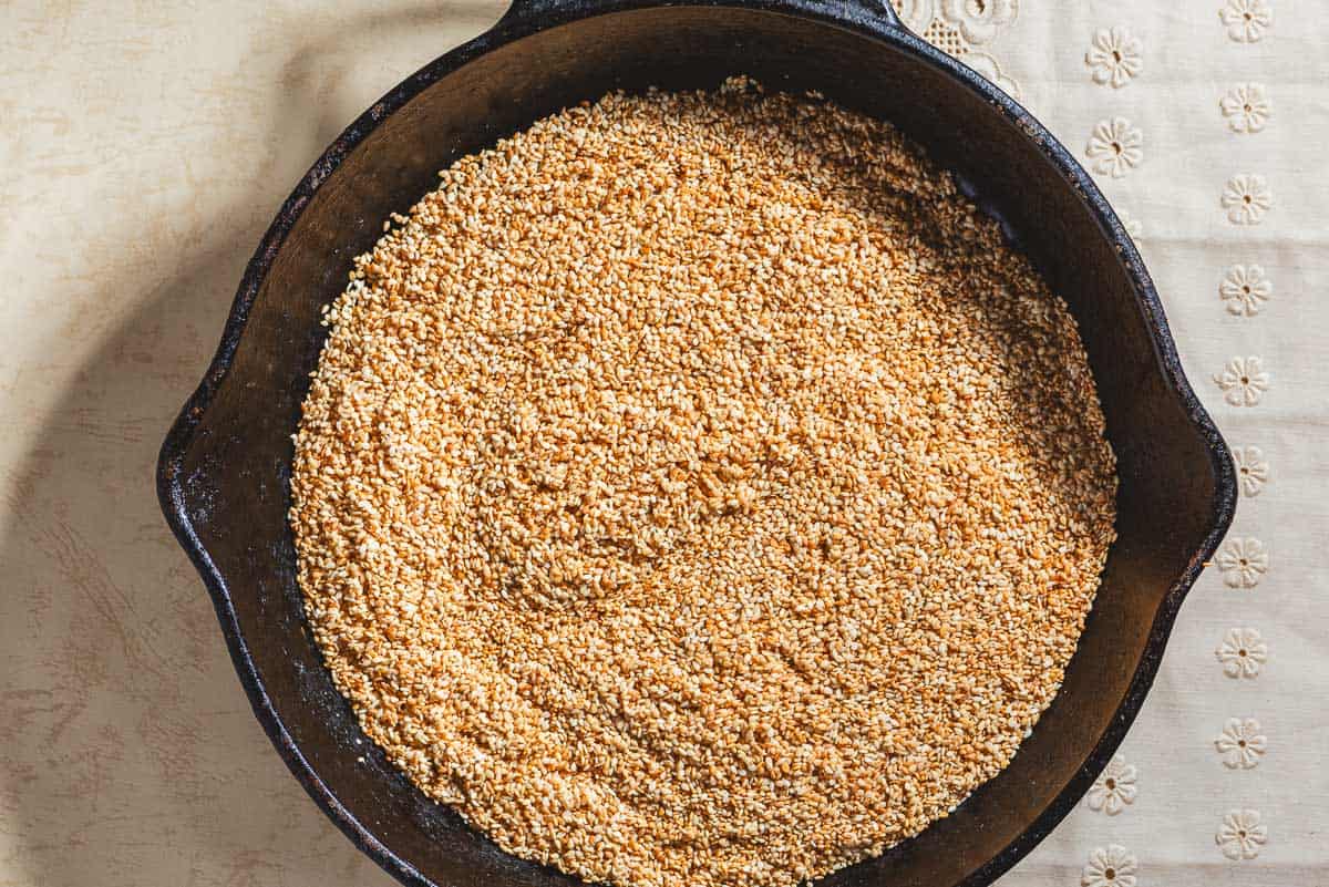 An overhead photo of toasted sesame seeds in a cast iron skillet.