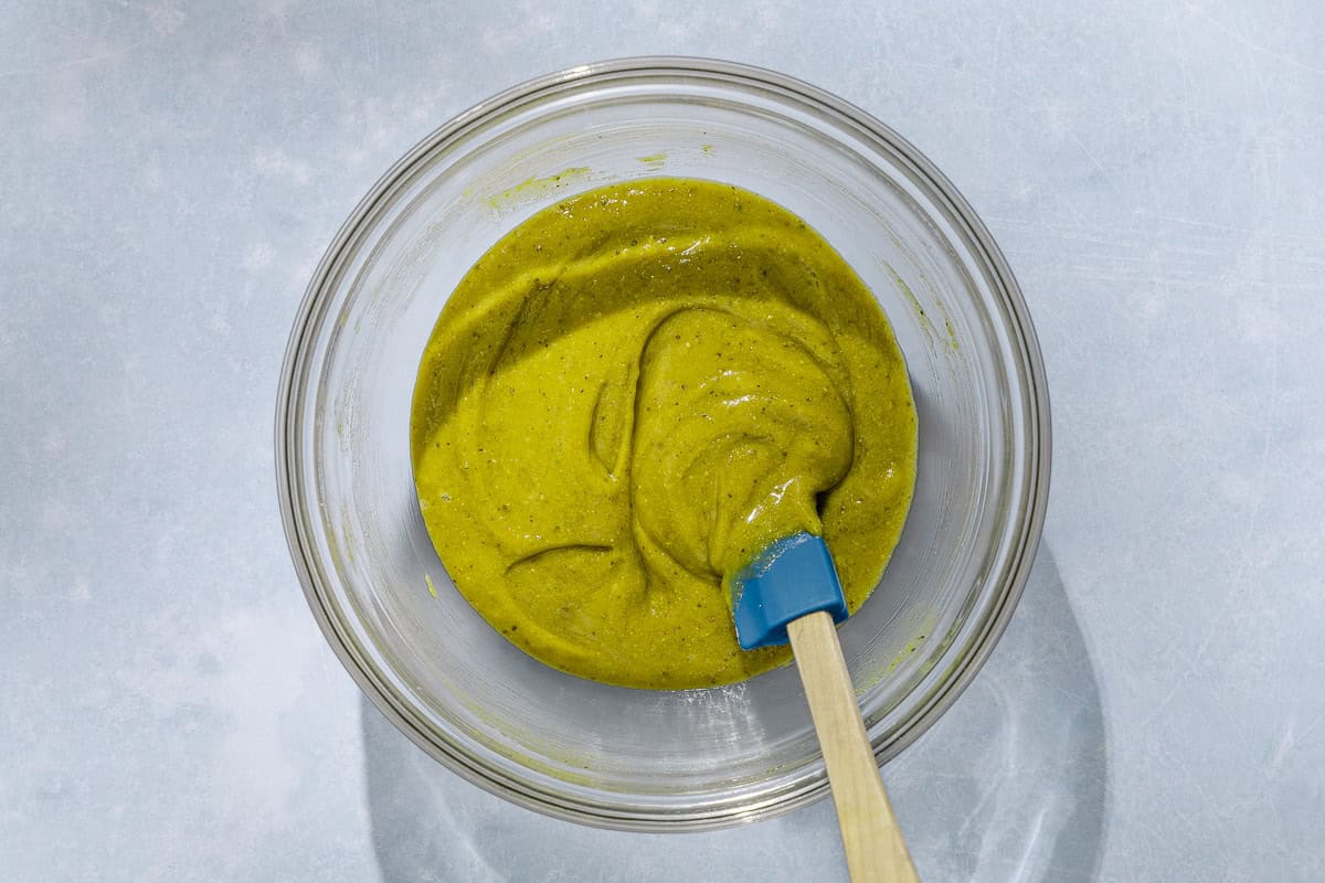 An overhead photo of the glaze for the pistachio cake in a bowl with a spatula.