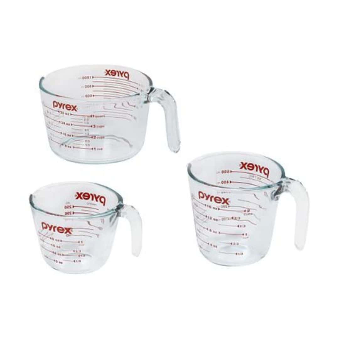 3 Pyrex measuring cups floating on a white background.