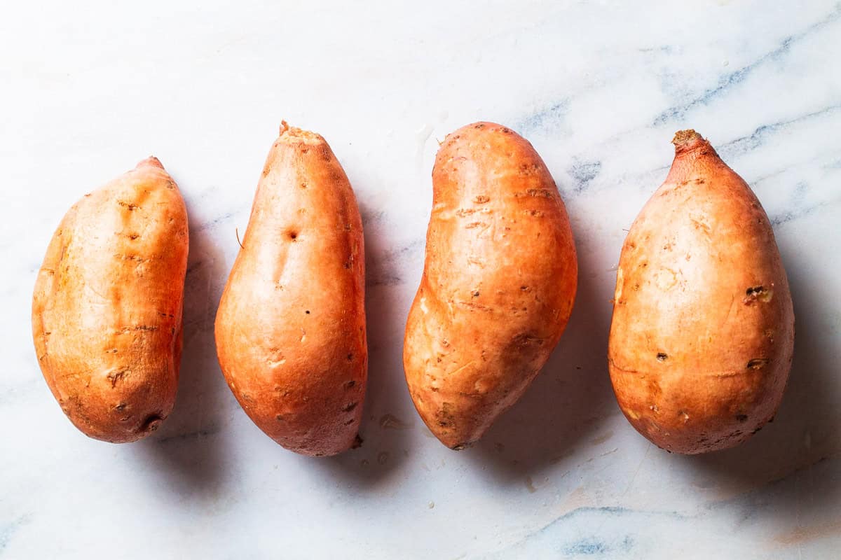 An overhead photo of 4 uncooked sweet potatoes.