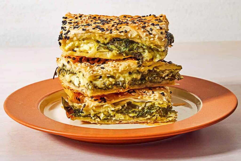 Three slices of turkish borek stacked on top of each other on a plate.