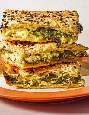 Three slices of turkish borek stacked on top of each other on a plate.