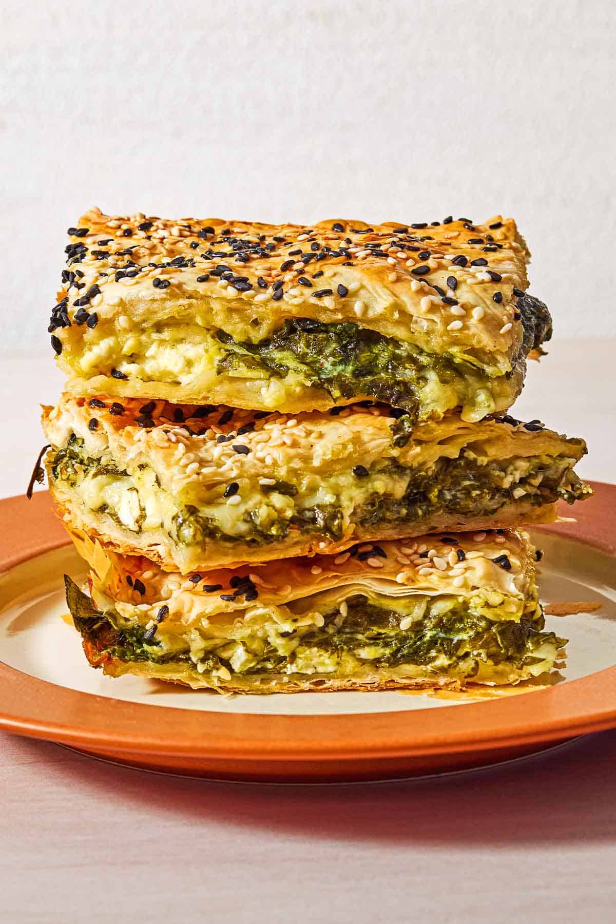 Three slices of turkish borek stacked on top of each other on a plate.