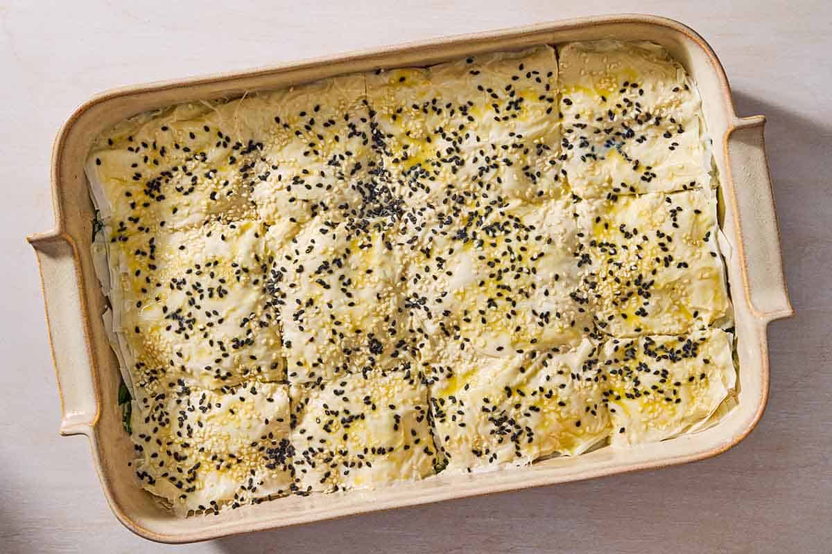 An overhead photo of sliced unbaked turkish borek in a baking dish.