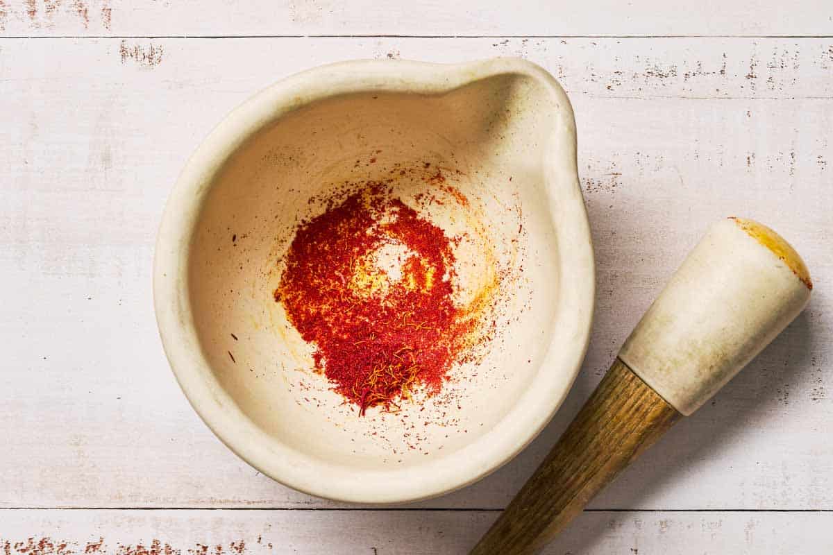 Ground saffron in a mortar with a pestle next to it.