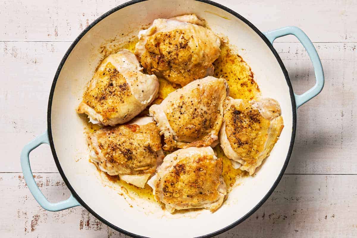 Chicken thighs being browned in a skillet.