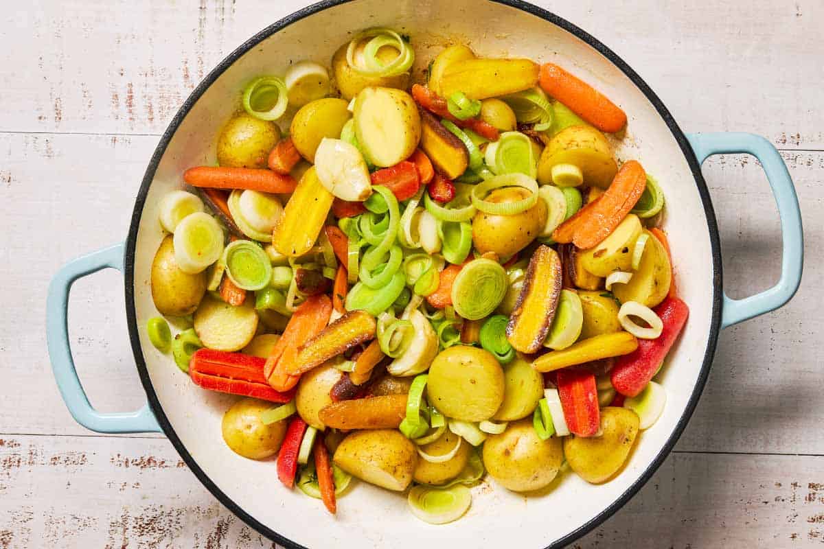 The vegetables and aromatics for the creamy saffron chicken cooking in a skillet.