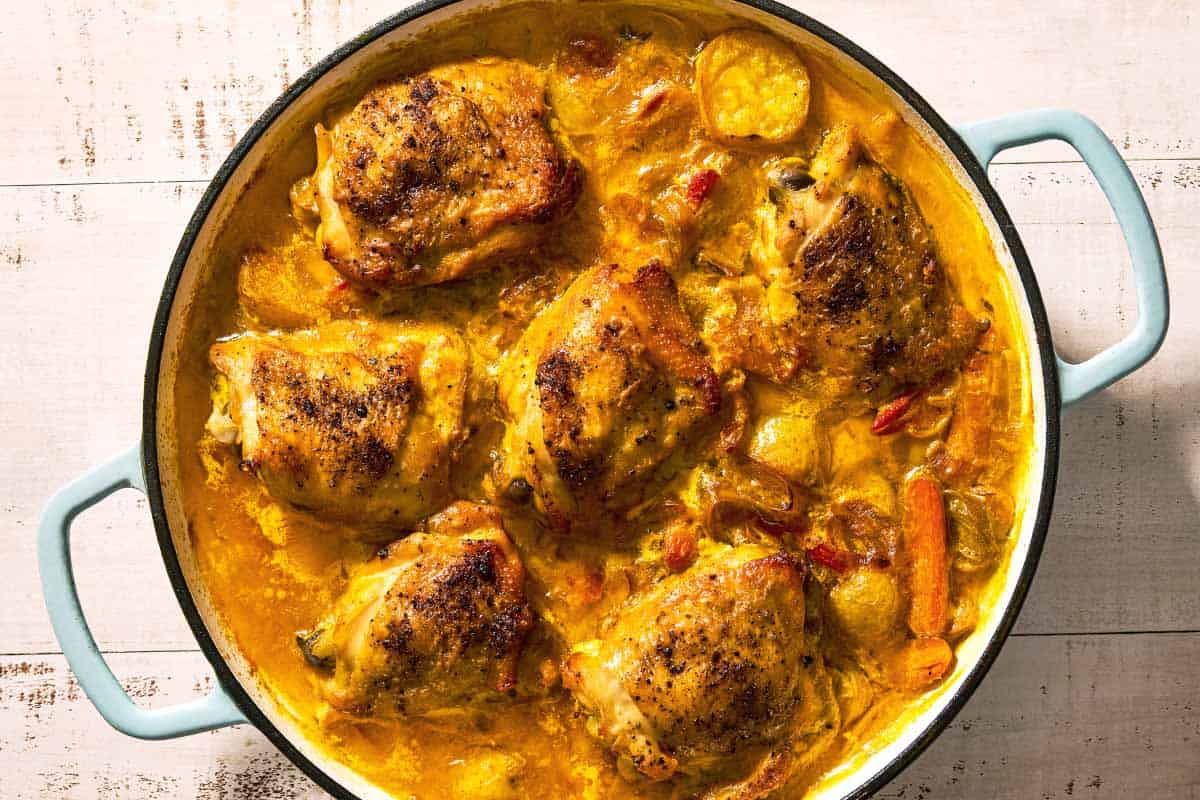 Creamy saffron chicken simmering in a skillet.