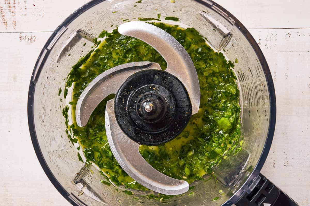 The cilantro dressing in the bowl of a food processor fitted with a blade.