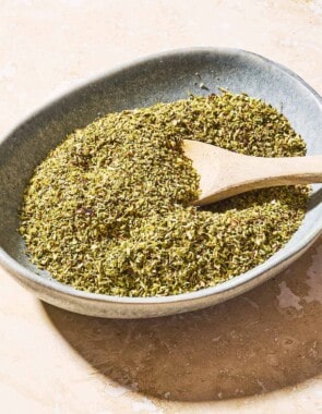 Dried oregano in a bowl with a wooden spoon.