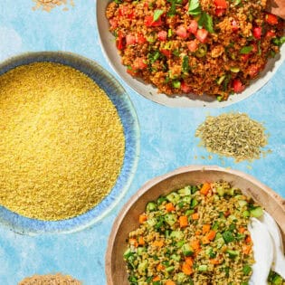 An overhead photo of bowls of kisir, couscous and herby freekeh salad along with 3 little piles of other grains.