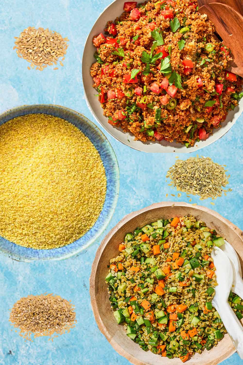 An overhead photo of bowls of kisir, couscous and herby freekeh salad  along with 3 little piles of other grains.