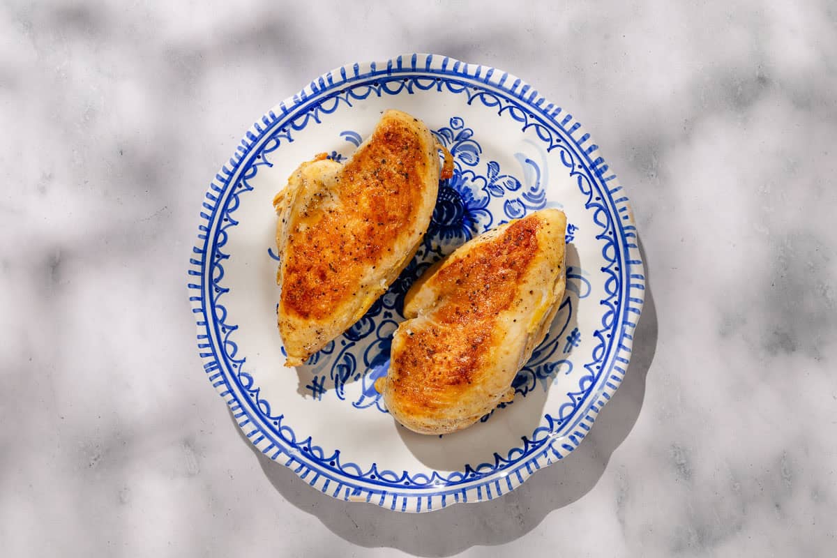 An overhead photo of 2 cooked chicken breasts on a plate.