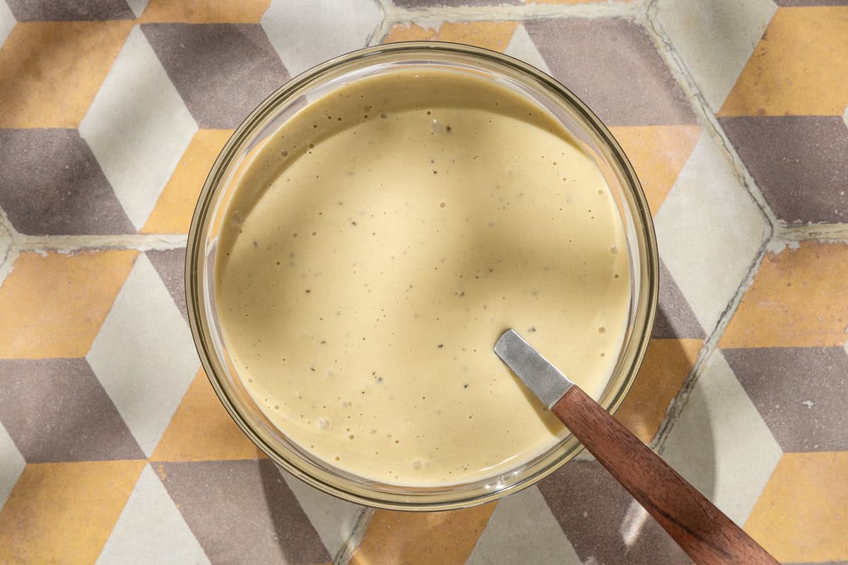 An overhead photo of the dressing for the salmon caesar salad in a bowl with a spoon.