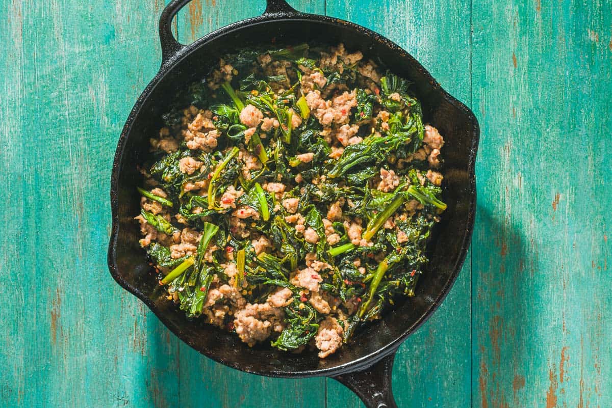 An overhead photo of the seasoned broccoli rabe and Italian turkey sausage after being cooked in a skillet.