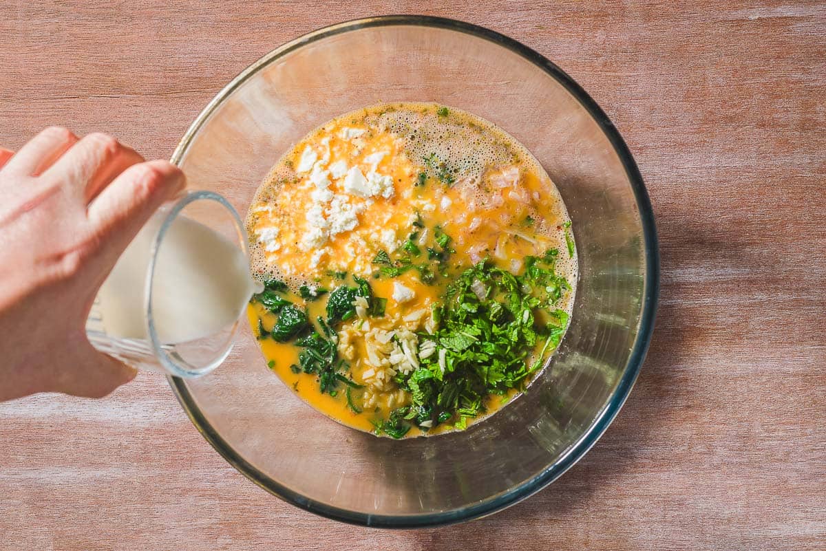 Milk being added to the rest of the ingredients for the frittata in a bowl.