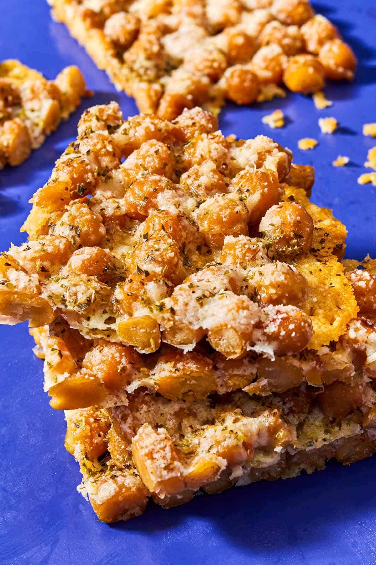 A close up of a stack of 3 baked parmesan crisps with chickpeas and oregano.