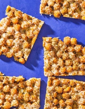 An overhead photo of baked parmesan crisps with chickpeas and oregano cut into 5 slices.